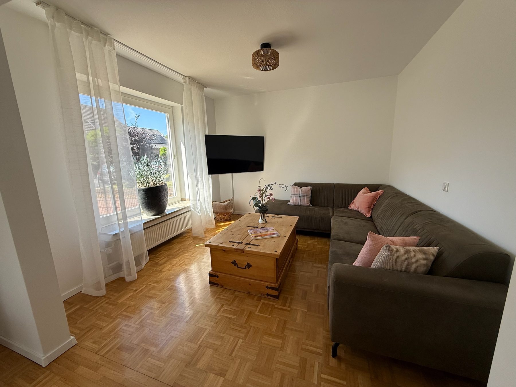 Helles Wohnzimmer mit großen Fenstern und TV